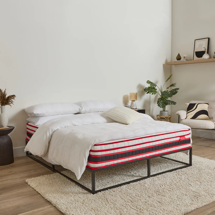 Bedroom with a bed featuring a striped mattress cover, white bedding, and decorative pillows.
