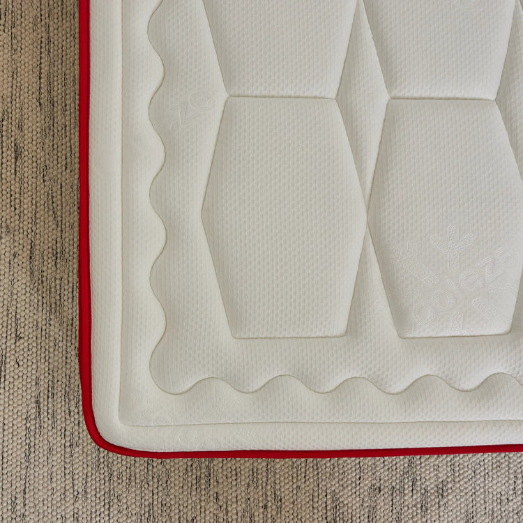 White quilted mat with red border on a textured surface