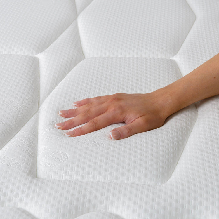 Hand touching a white mattress to check its softness