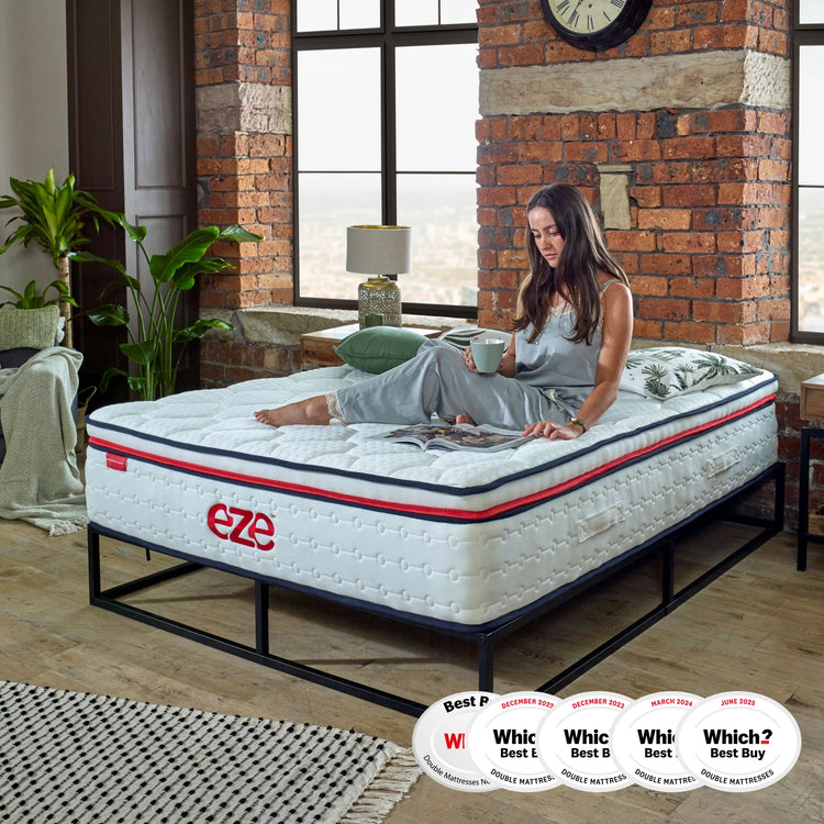 Woman relaxing on a mattress with 'Eze' branding in a room with brick walls and large windows.