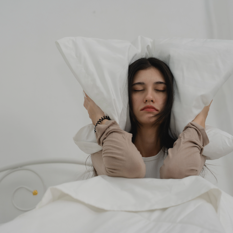 women_in_bed_sat_up_with_pillow_around_her_head
