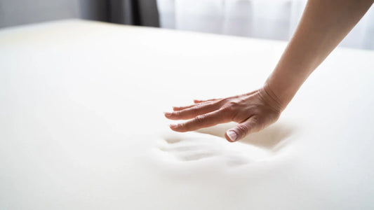 womens hand touching a memory foam mattress