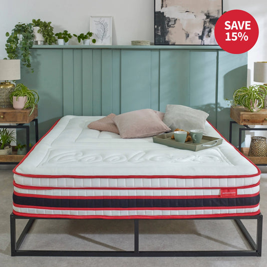 Mattress on a bed frame with decorative pillows and a tray, in a room setting.