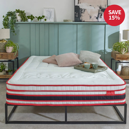 Mattress on a bed frame with decorative pillows and a tray, in a room setting.