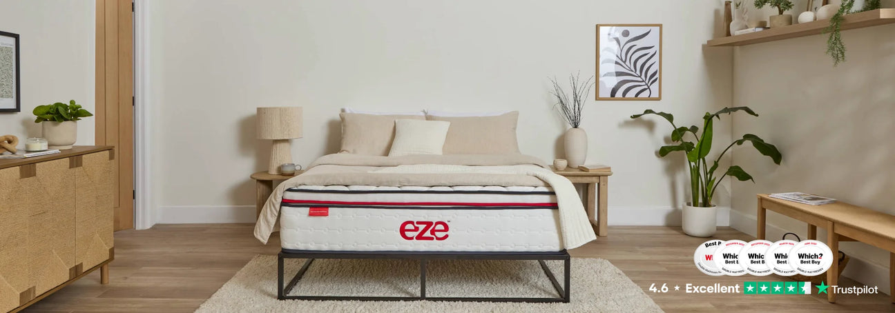 EZE HYBRID MAX IN A NEUTRALLY STYLED BEDROOM ON A BLACK METAL BED FRAME WITH PLANTS AND PRINTS ON THE WALL