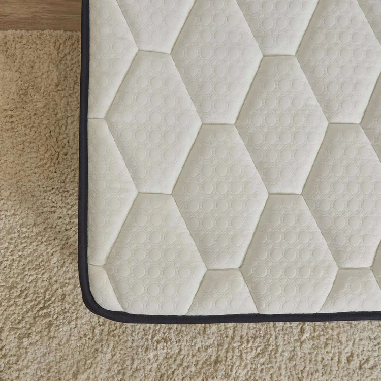 Hexagonal patterned eze hybrid max mattress surface on a wooden floor