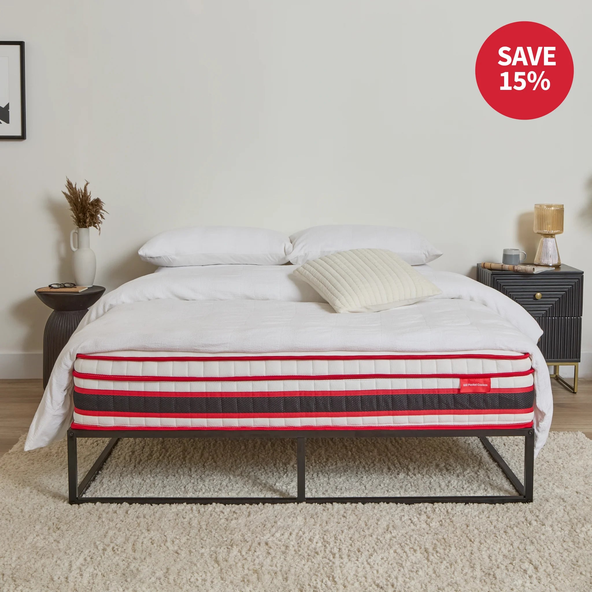 Mattress on a bed frame with decorative pillows and a tray, in a room setting.