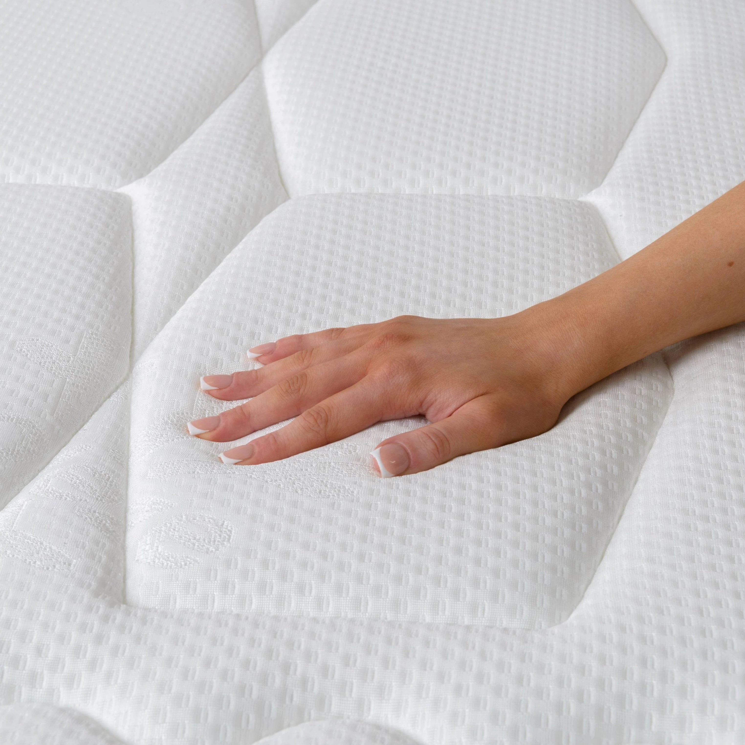Hand touching a white mattress to check its softness