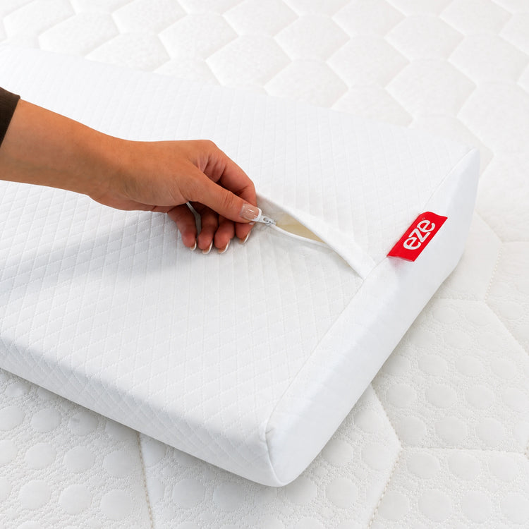 Hand opening a eze white pillow protector with eze logo on a hybrid ultra mattress