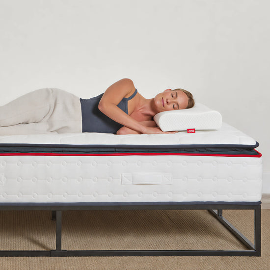 women lying on a hybrid mattress with a visible eze brand logo, on a plain background