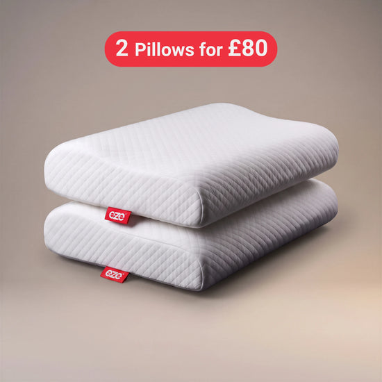 Two white quilted memory foam EZE pillows stacked on a beige gradient background with a red promotional badge that reads '2 Pillows for £80'. Each pillow has a small red eze fabric tag with the brand name 'eze'.